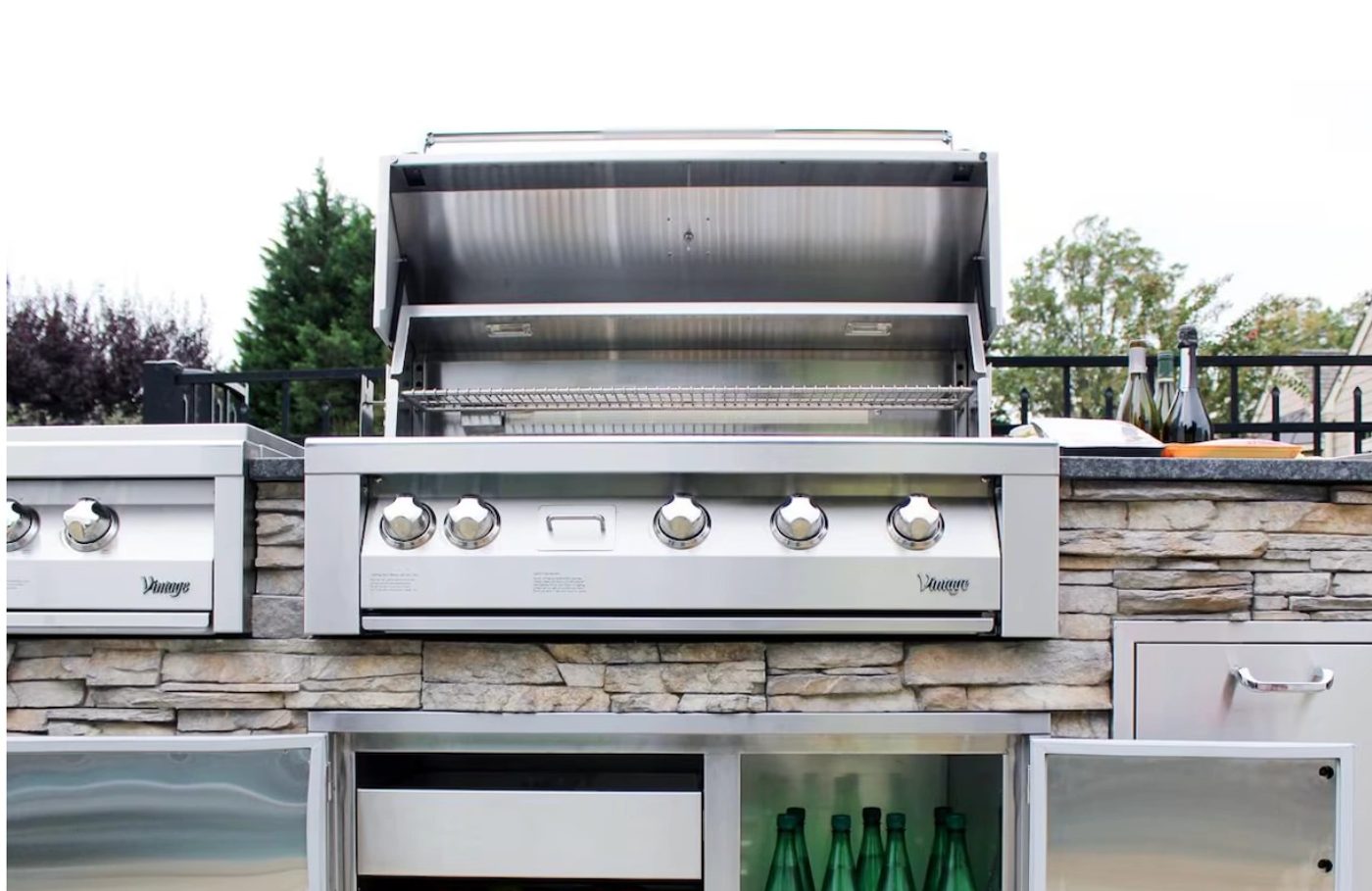 Built-in stainless grill set into a stacked stone surround with granite counters either side