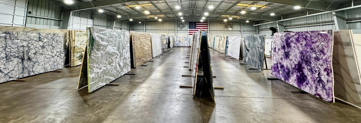 Rows of granite and quartzite slabs standing in the KB Countertops warehouse